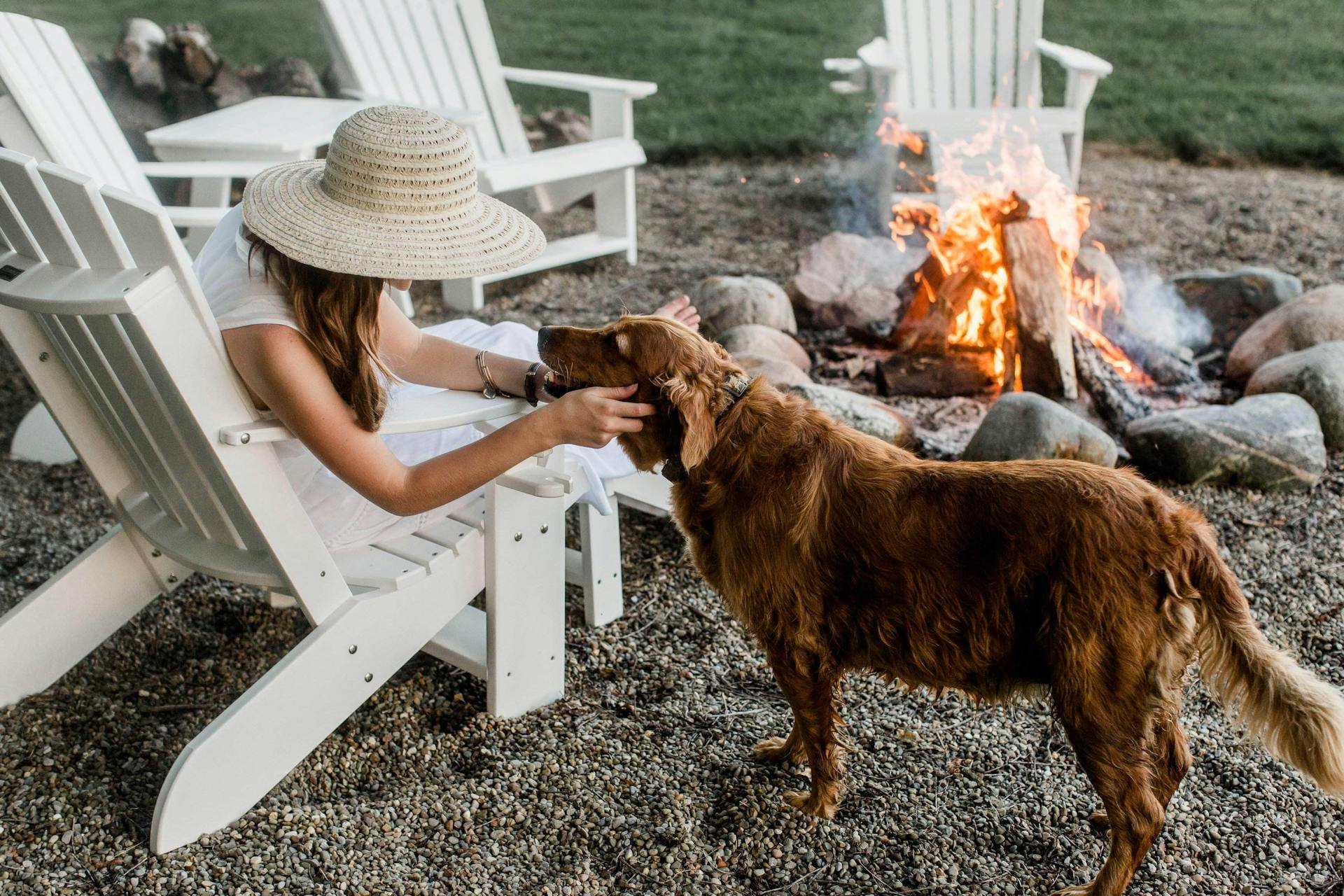 Heritage Adirondack Chairs in white around a campfire with a dog